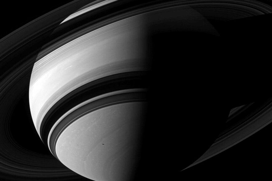 Os anéis bem visíveis e Janus é visto sobre o polo norte de Saturno nesta imagem, enquanto a sombra de Mimas desliza sobre Saturno.